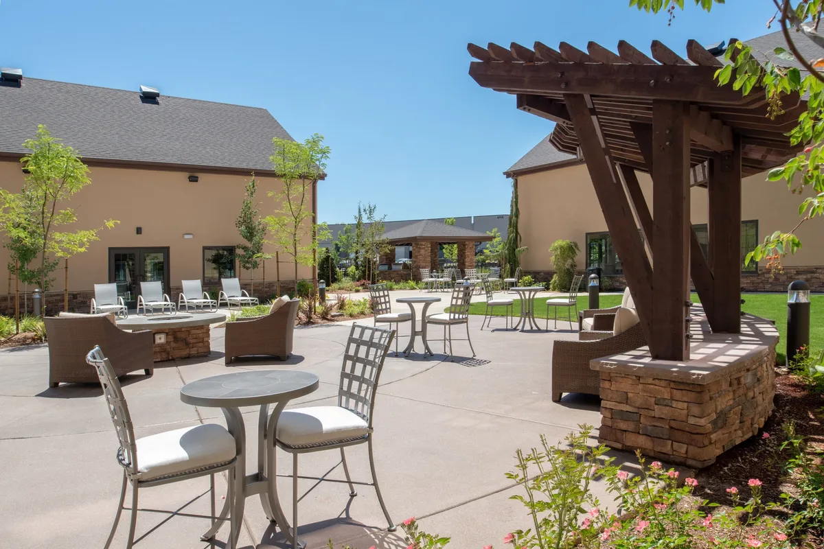 An outdoor area set beneath a stylish pergola, with comfortable seating and lush landscaped greenery. The space is ideal for relaxing, socializing, or enjoying outdoor meals, hinting at the communal BBQ experience mentioned in the section.