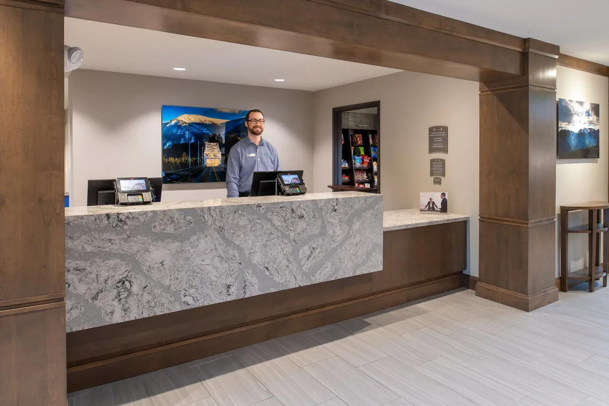 A professional and welcoming reception area with a friendly staff member at the front desk and vibrant artwork on the wall, setting the tone for efficient guest service and a pleasant arrival experience.