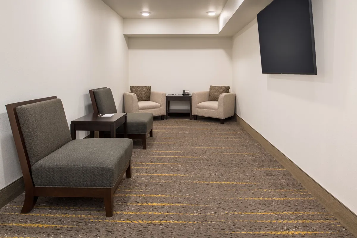 A cozy shared interior space featuring two comfortable armchairs, a small table, a television, and a striped rug. The ambiance is serene and inviting—ideal for casual conversations, relaxation, or enjoying a quiet moment together.
